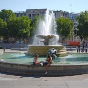 People sit by the fountains in Trafalgar Square, central London.