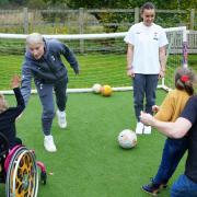 Bethany England and Hayley Raso on the pitch with Willow and Ruby at Noah's Ark Children's Hospice