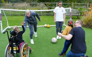 Bethany England and Hayley Raso on the pitch with Willow and Ruby at Noah's Ark Children's Hospice